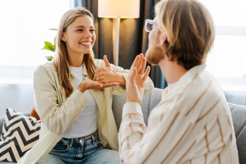 Eine Frau und ein Mann unterhalten sich auf dem Sofa in Gebärdensprache
