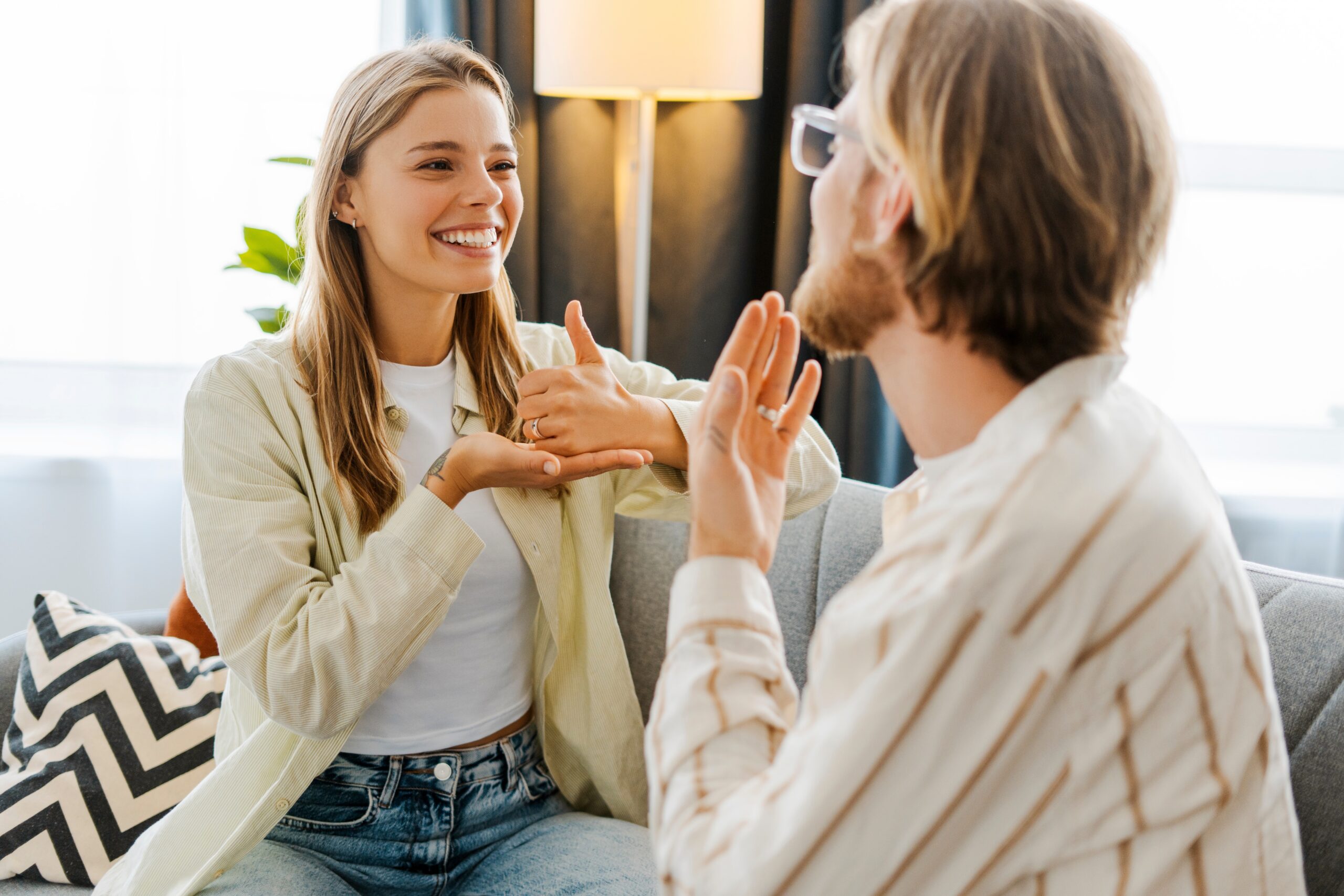 Eine Frau und ein Mann unterhalten sich auf dem Sofa in Gebärdensprache